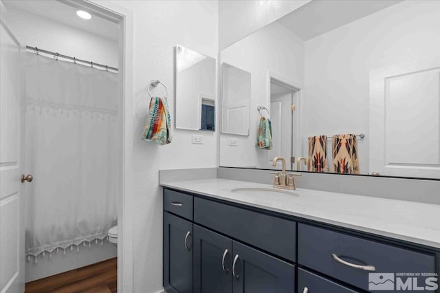 bathroom featuring curtained shower, toilet, wood finished floors, and vanity