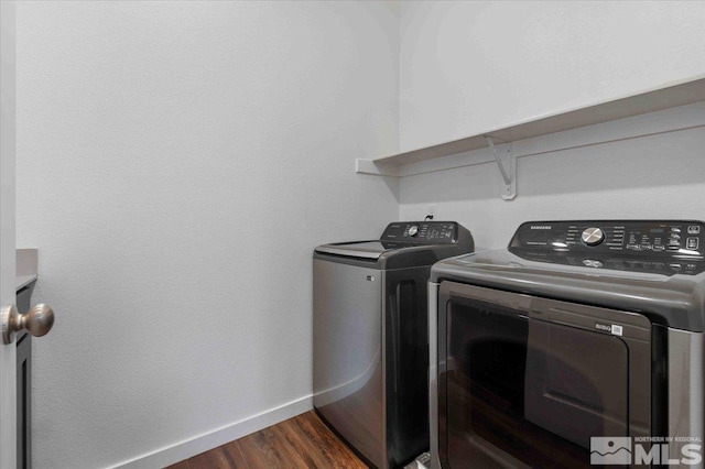 washroom featuring washing machine and clothes dryer, laundry area, baseboards, and dark wood-style flooring