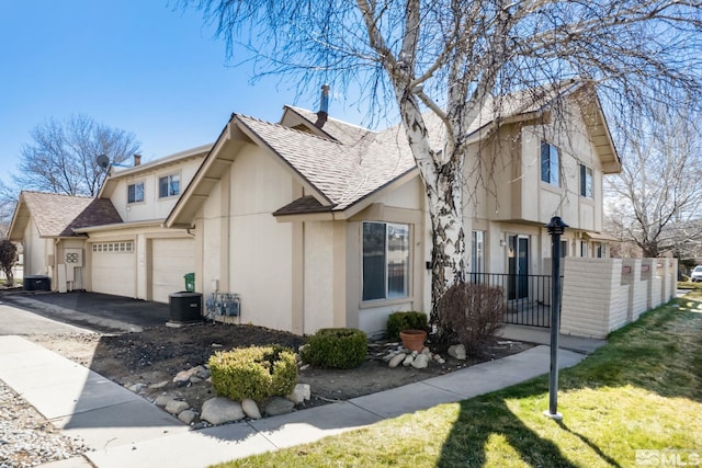 view of side of property featuring stucco siding, fence, aphalt driveway, and a shingled roof