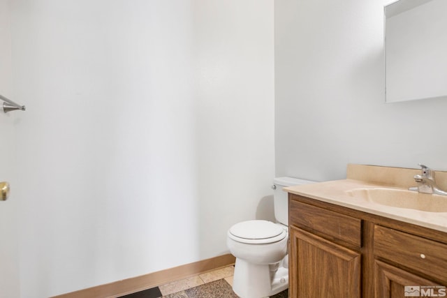 half bath with tile patterned floors, toilet, vanity, and baseboards