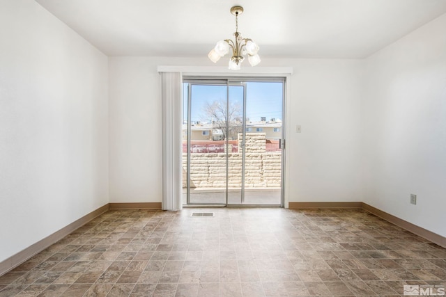 spare room featuring a notable chandelier, visible vents, and baseboards