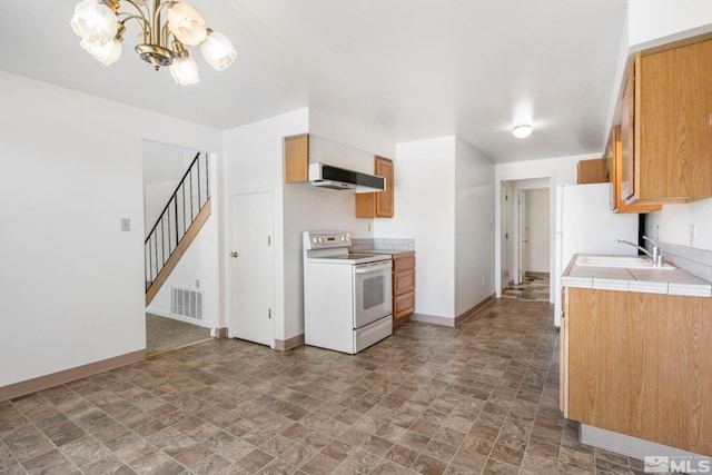 kitchen with visible vents, under cabinet range hood, a sink, white appliances, and a chandelier