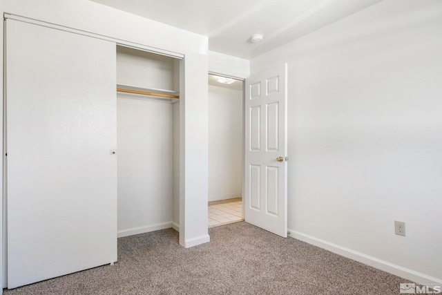 unfurnished bedroom with a closet, baseboards, and carpet