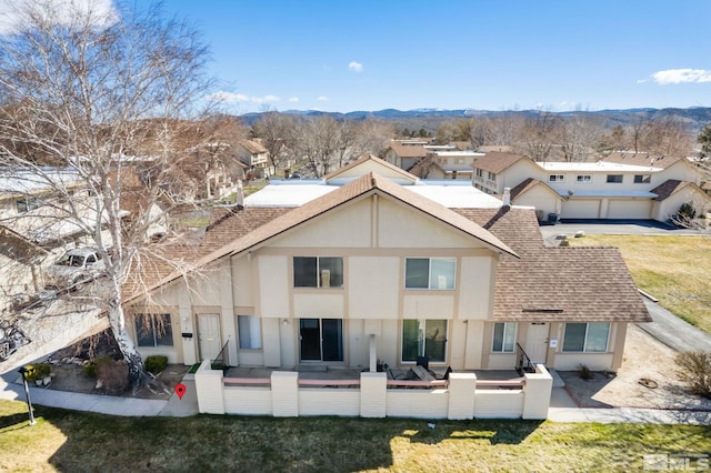 back of property with roof with shingles, stucco siding, a lawn, a mountain view, and a patio