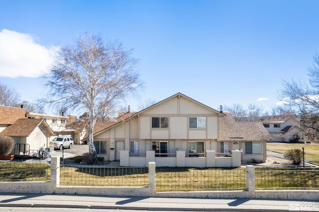 view of front of home featuring a front lawn, stucco siding, a fenced front yard, and a shingled roof