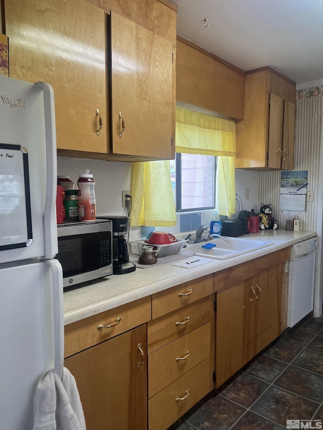 kitchen with white appliances, brown cabinetry, light countertops, and a sink