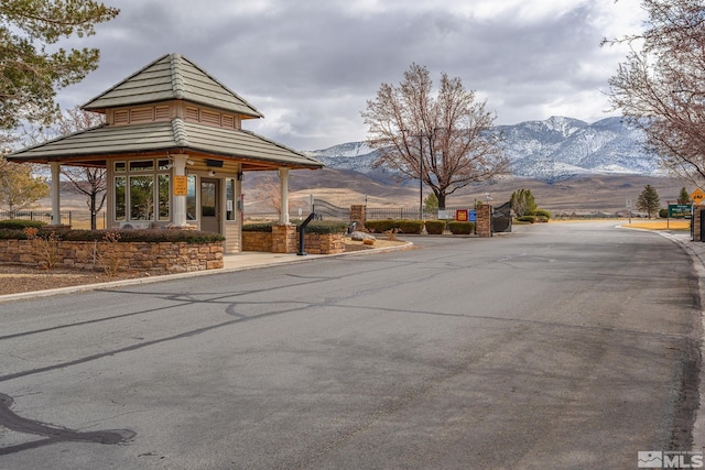 view of road with a gated entry, curbs, and a mountain view