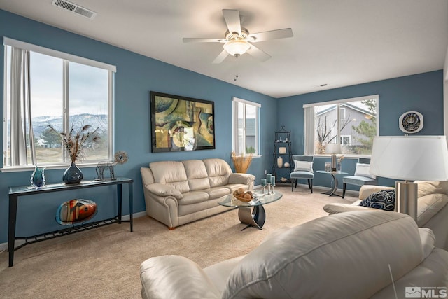 carpeted living area with a ceiling fan, plenty of natural light, baseboards, and visible vents