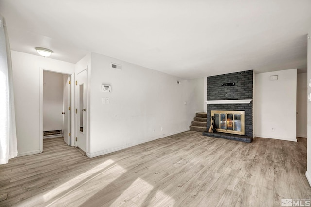 unfurnished living room featuring visible vents, light wood-style flooring, a brick fireplace, and baseboard heating