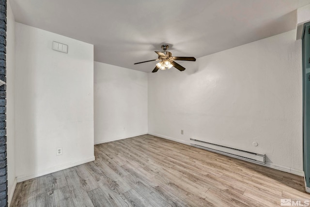 spare room with visible vents, a ceiling fan, a baseboard heating unit, wood finished floors, and baseboards