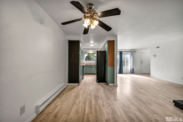 unfurnished living room featuring ceiling fan, baseboards, baseboard heating, and light wood-style flooring