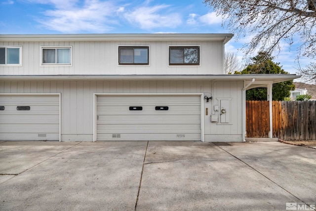 garage featuring driveway and fence