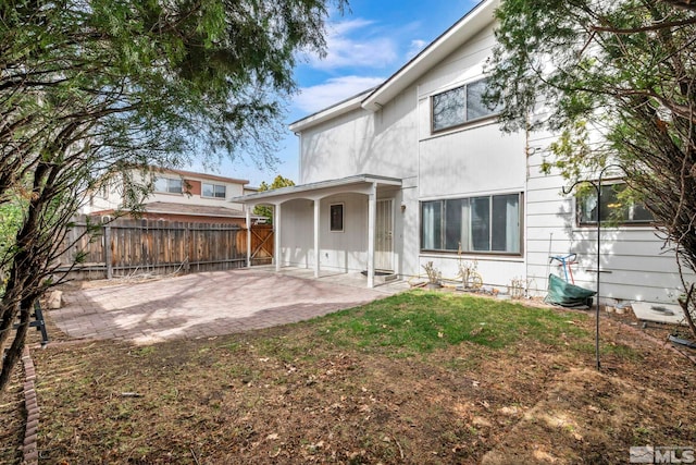 rear view of house with a patio, a lawn, and fence