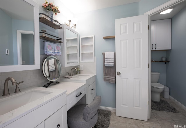 bathroom featuring double vanity, toilet, tasteful backsplash, and a sink