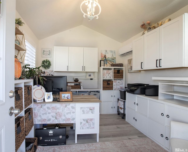 kitchen with a wall mounted AC, white cabinetry, light wood-style floors, an inviting chandelier, and lofted ceiling