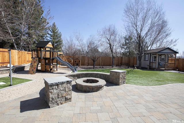 view of patio / terrace with an outdoor structure, a playground, a fenced backyard, and an outdoor fire pit