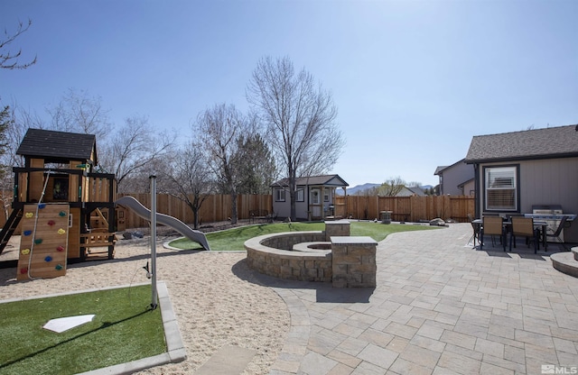 view of patio with an outbuilding, a playground, a fenced backyard, and a shed