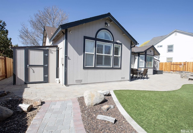 rear view of property with a fenced backyard, a shed, an outdoor structure, crawl space, and a patio area