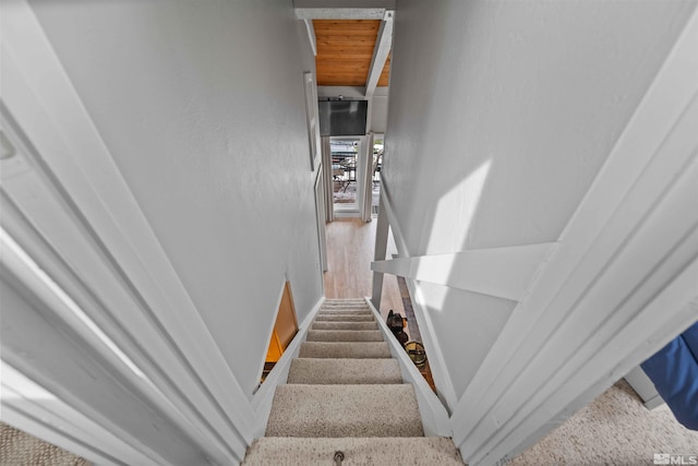 stairway with wooden ceiling and wood finished floors