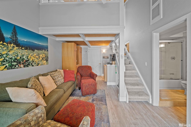 living area featuring visible vents, baseboards, wood finished floors, and stairs