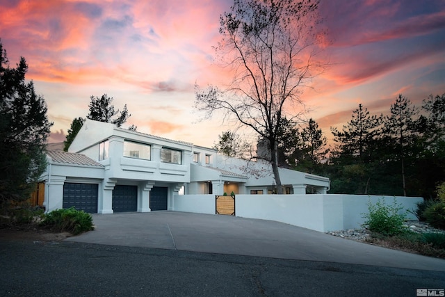 view of front of home with a fenced front yard, a garage, driveway, and stucco siding