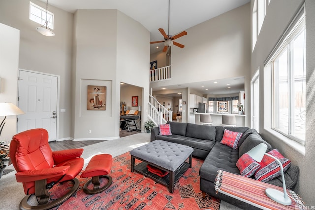 living room with baseboards, a healthy amount of sunlight, a towering ceiling, and stairs