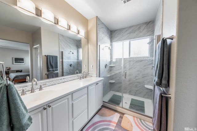 ensuite bathroom featuring a sink, a marble finish shower, ensuite bathroom, and double vanity