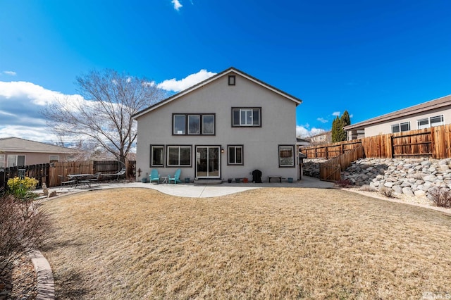 rear view of property with a patio area, stucco siding, a yard, and a fenced backyard