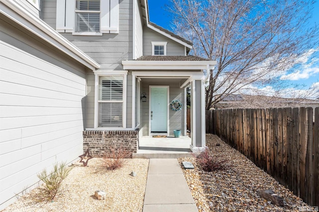 entrance to property featuring covered porch and fence