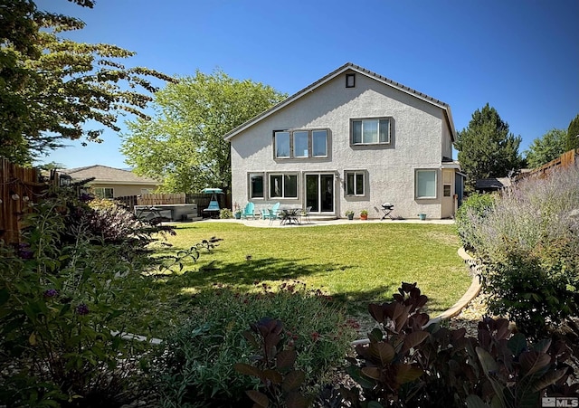 rear view of property featuring stucco siding, a lawn, a fenced backyard, and a patio area