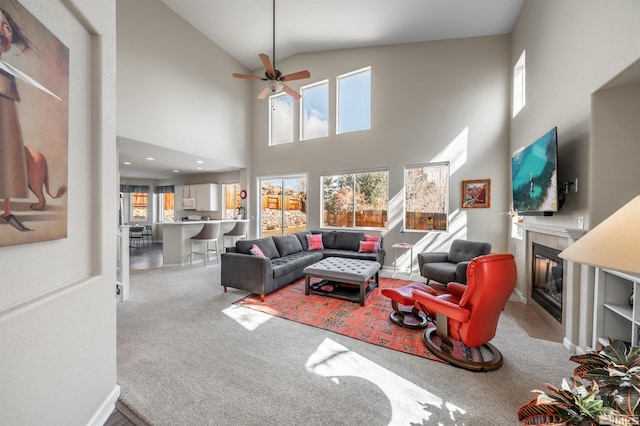 carpeted living room with a fireplace, ceiling fan, and vaulted ceiling