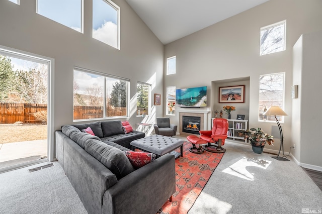 living room featuring a glass covered fireplace, a healthy amount of sunlight, baseboards, and visible vents