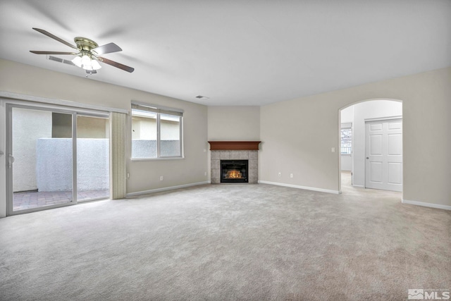 unfurnished living room featuring arched walkways, carpet flooring, a fireplace, and baseboards