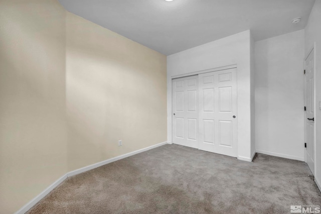 unfurnished bedroom featuring a closet, baseboards, and carpet flooring