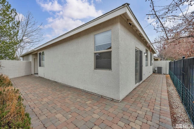 rear view of house with a patio area, stucco siding, cooling unit, and a fenced backyard