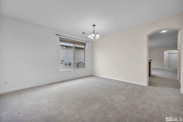 carpeted empty room featuring baseboards, arched walkways, and a chandelier