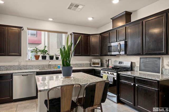 kitchen featuring visible vents, light stone counters, recessed lighting, stainless steel appliances, and a sink