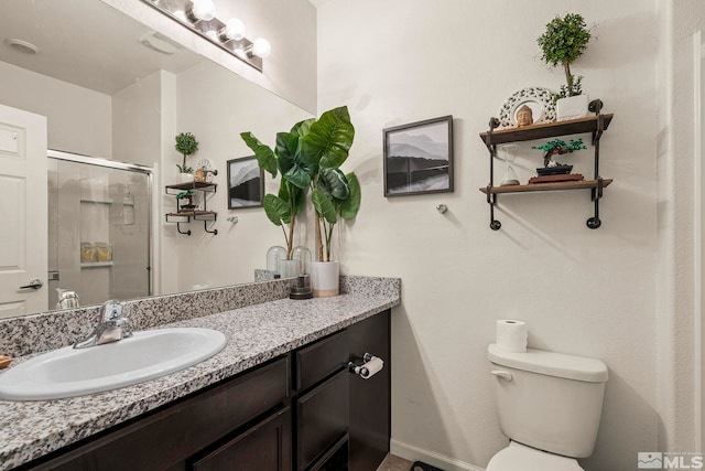 bathroom featuring baseboards, a shower stall, vanity, and toilet