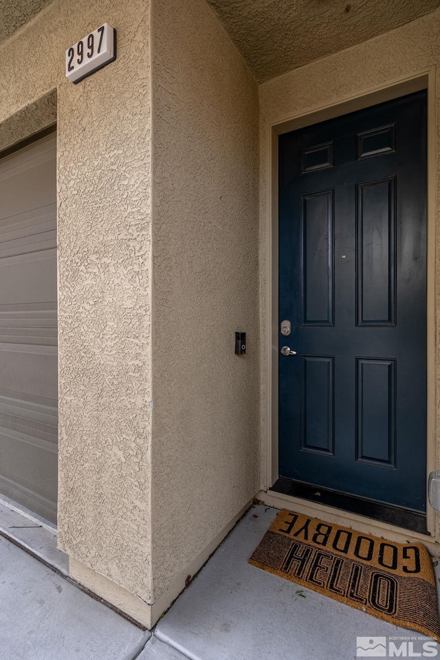 entrance to property featuring a garage and stucco siding