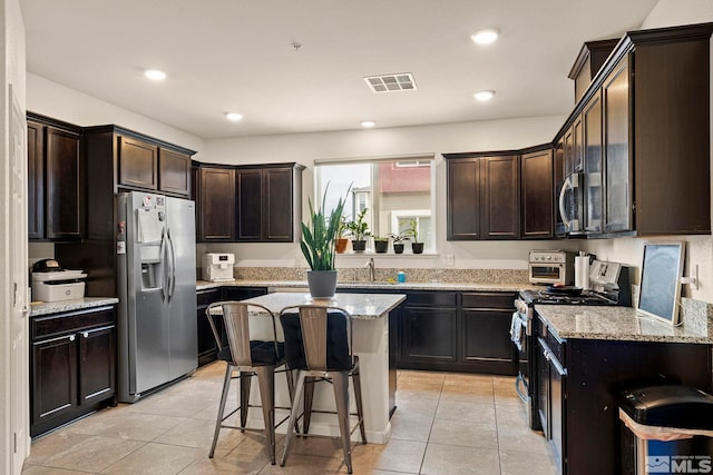 kitchen with visible vents, a kitchen breakfast bar, dark brown cabinetry, and appliances with stainless steel finishes