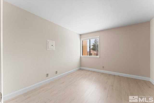 unfurnished room with baseboards and light wood-style floors