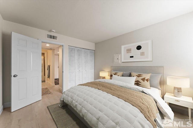 bedroom with a closet, visible vents, and light wood-style floors