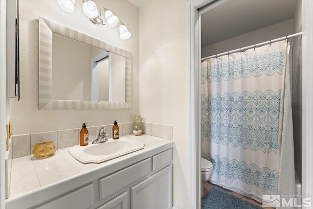 bathroom with curtained shower, toilet, and vanity