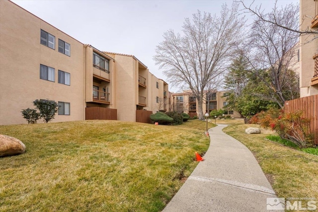 view of property's community featuring a yard and fence