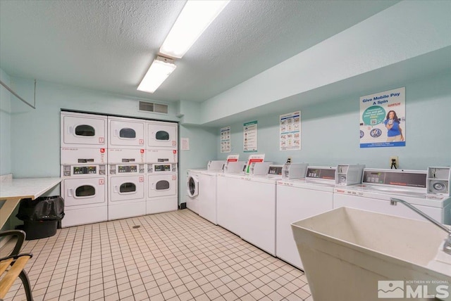 community laundry room with washer and clothes dryer, a sink, visible vents, and stacked washer and dryer