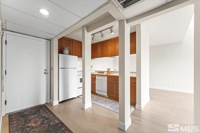 kitchen with light wood-type flooring, white appliances, baseboards, and brown cabinetry