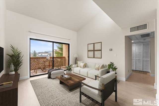 living room with visible vents, baseboards, high vaulted ceiling, and light wood-style flooring