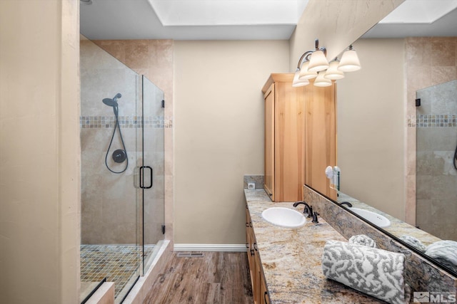 full bath with visible vents, wood finished floors, a shower stall, baseboards, and vanity