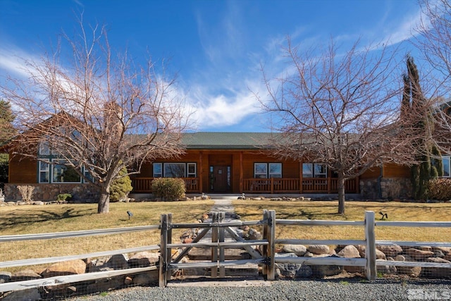 single story home with a fenced front yard, stone siding, covered porch, and a front lawn