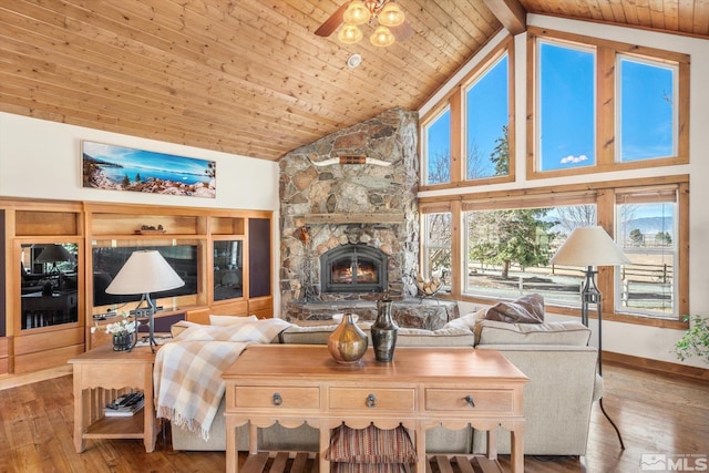 living area with a stone fireplace, wooden ceiling, wood finished floors, and high vaulted ceiling